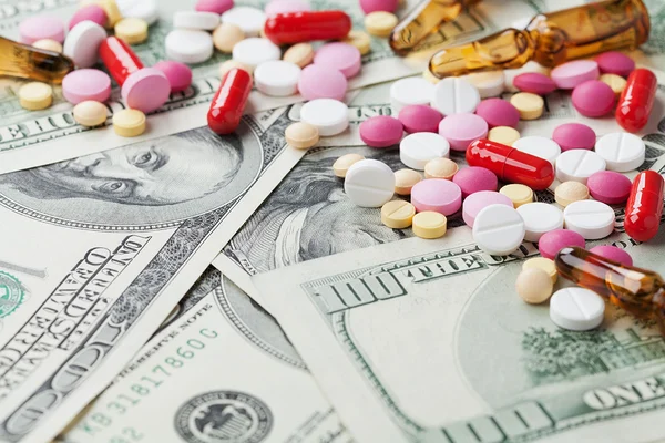 Heap of pharmaceutical drug and medicine pills scattered on dollar cash money, cost of drug abuse concept