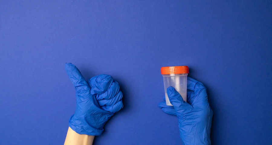 Gloved hands holding a drug test sample and giving a thumbs up
