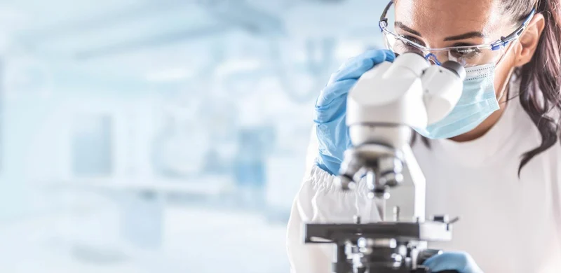 Female scientist viewing microscope