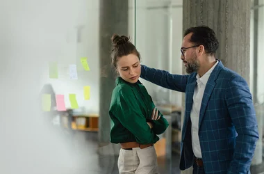 Oncomfortabele foto van een vrouw en een collega die over haar heen staat gebogen