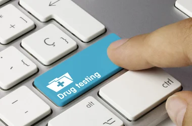 Finger pressing a button on a keyboard labeled "Drug Testing"
