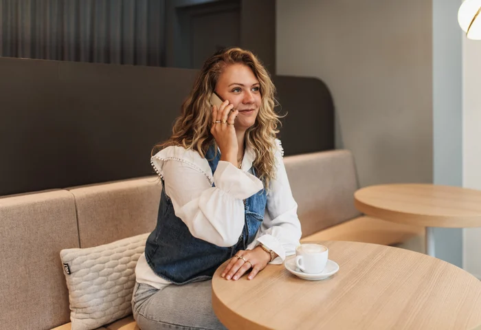 Woman with curly hair sitting in a sofa in an office space with a computer