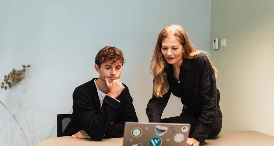 två anställda diskuterar arbete på bärbar dator
