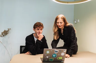 två anställda diskuterar arbete på bärbar dator