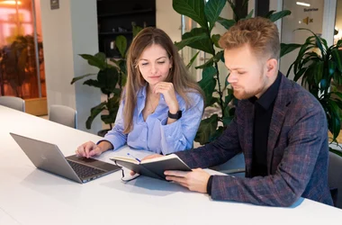 Zwei Kolleg:innen, die gemeinsam an einem Computer arbeiten