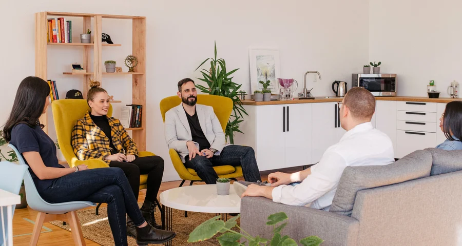 Grupp med människor sitter i en soffgrupp i en skandinavisk kontorsmiljö.