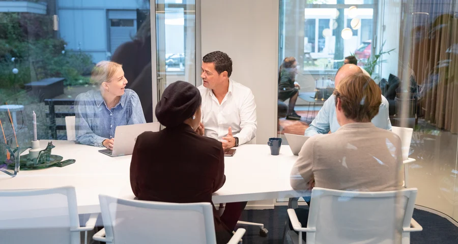 Grupp av kollegor sitter runt ett bord och diskuterar