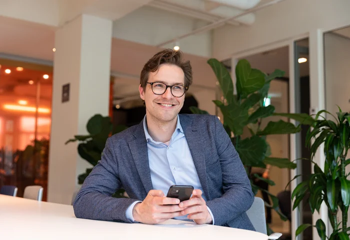En leende man scrollar på sin mobiltelefon