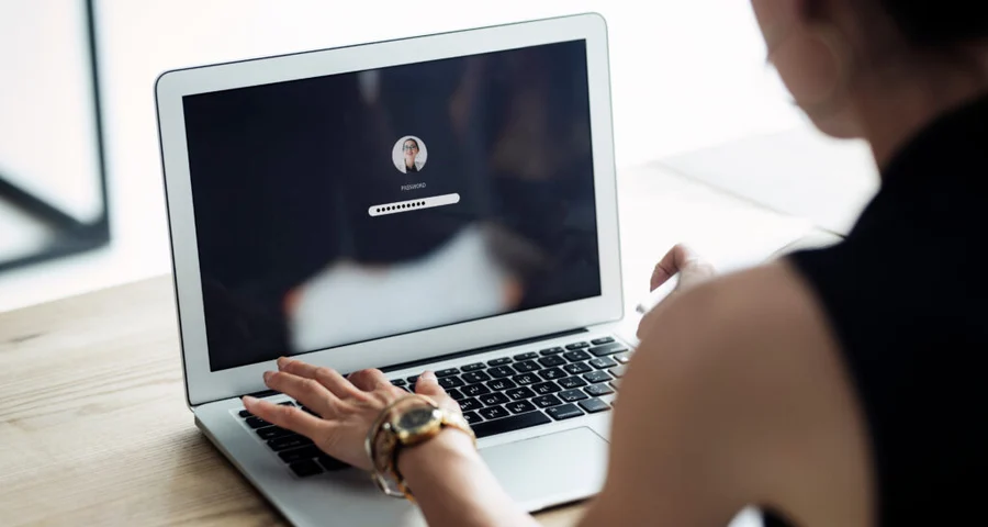 The foundation for background checks for national and international companies. Woman sitting in front of a computer writing her password.