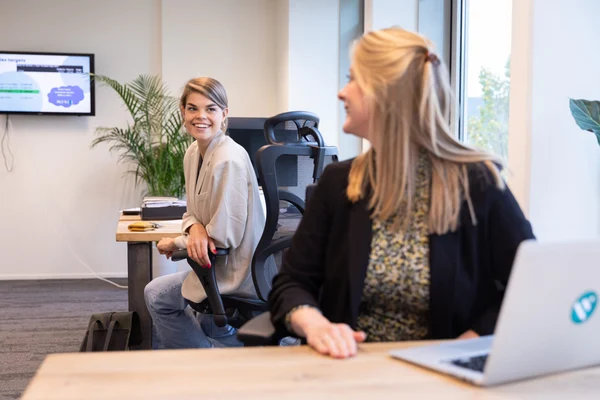 Två medarbetare sitter vid sina arbetsplatser och pratar om hur testerna kan genomföras på bästa sätt